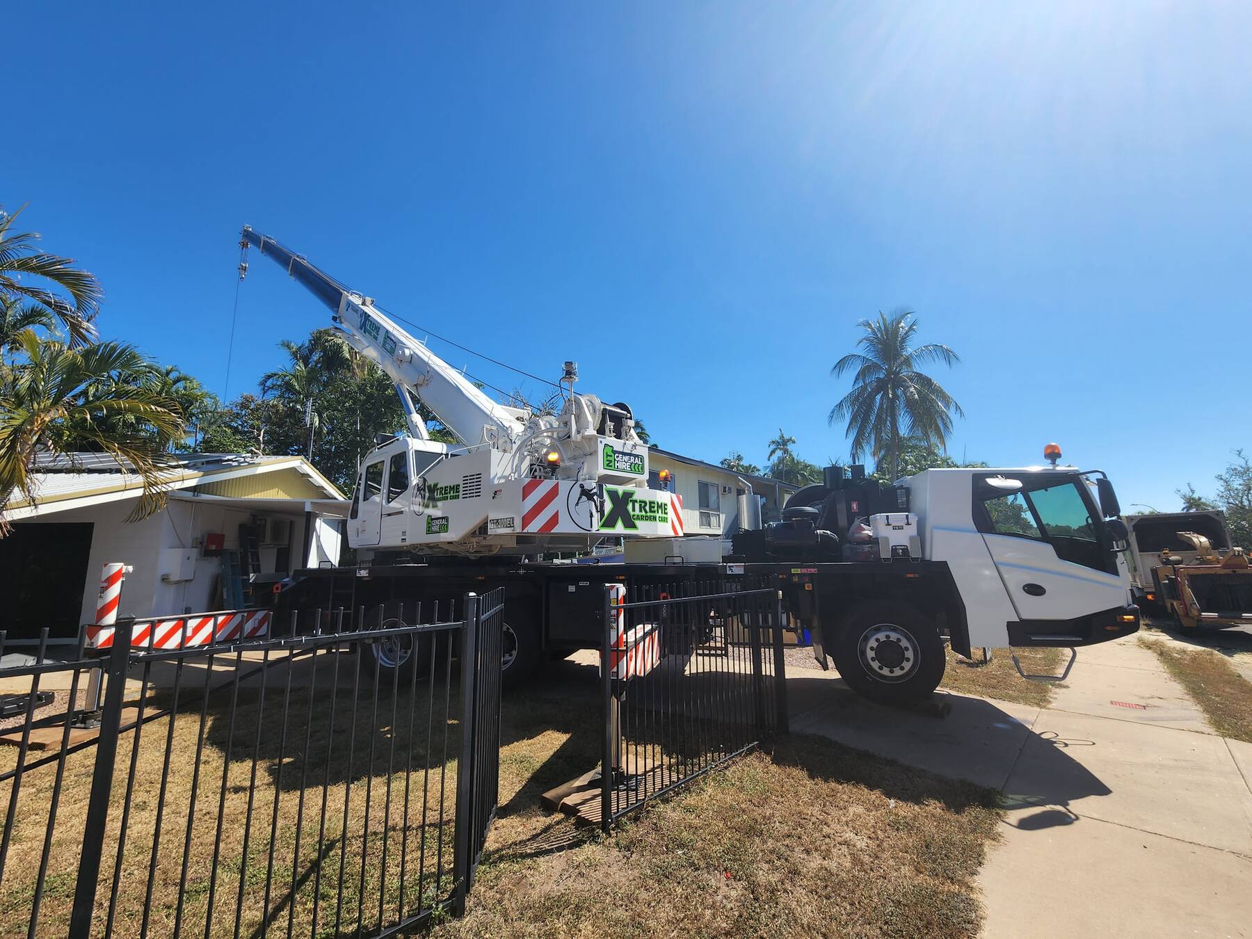 Xtreme Garden Care crane lifting a tree section over a Darwin home